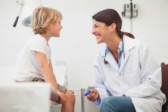Doctor-smiling-to-a-child-in-examination-room-web